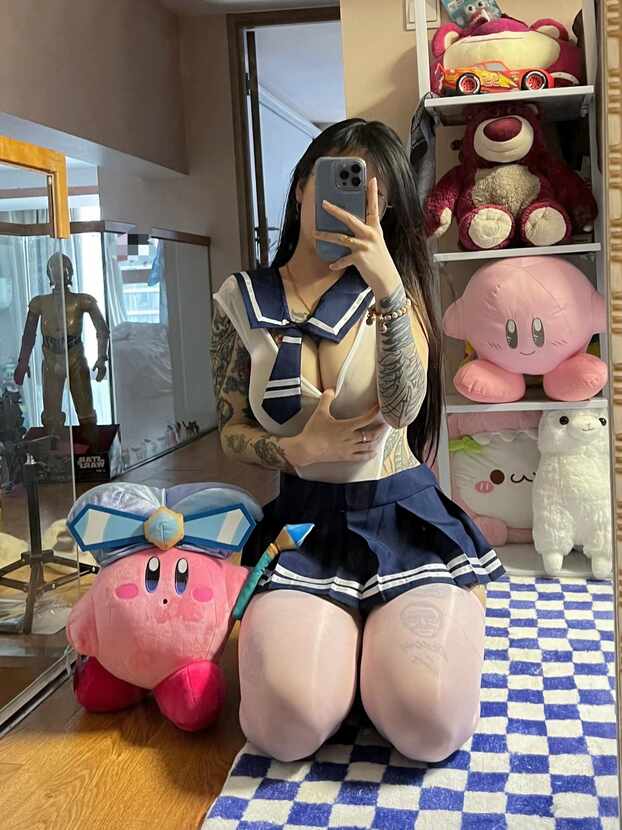 模特卡通百科老王身穿改良水手服上衣、海军蓝短裙和纹身图案丝袜，戴眼镜，在镜子前自拍全身，手臂有纹身