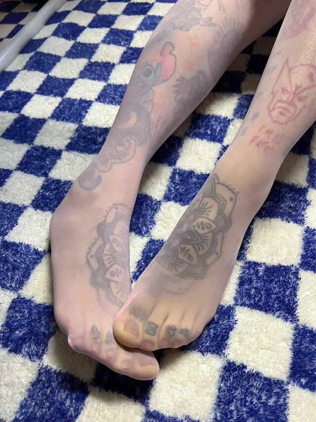模特卡通百科老王穿着带有纹身/印花图案的肉色或粉色丝袜的足部特写，可见史迪奇、金刚狼爪印等图案