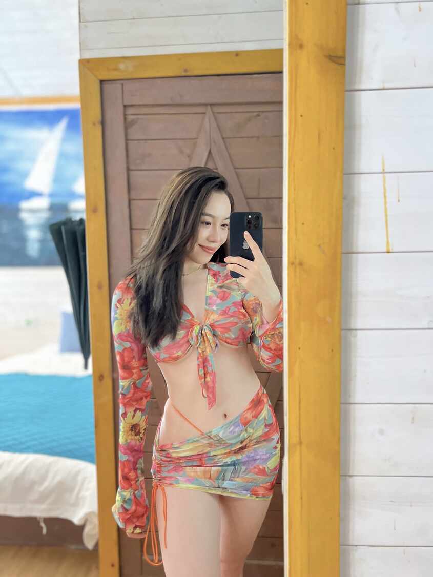 模特铁锤姐姐身穿彩色碎花绑带长袖上衣和抽绳短裙，对着镜子进行自拍