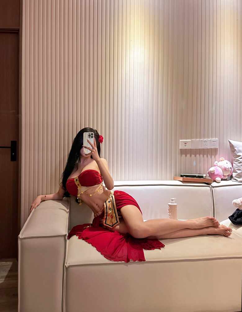 模特黎允熙baby身穿红色抹胸和金色饰品套装，在沙发上躺姿抬腿自拍