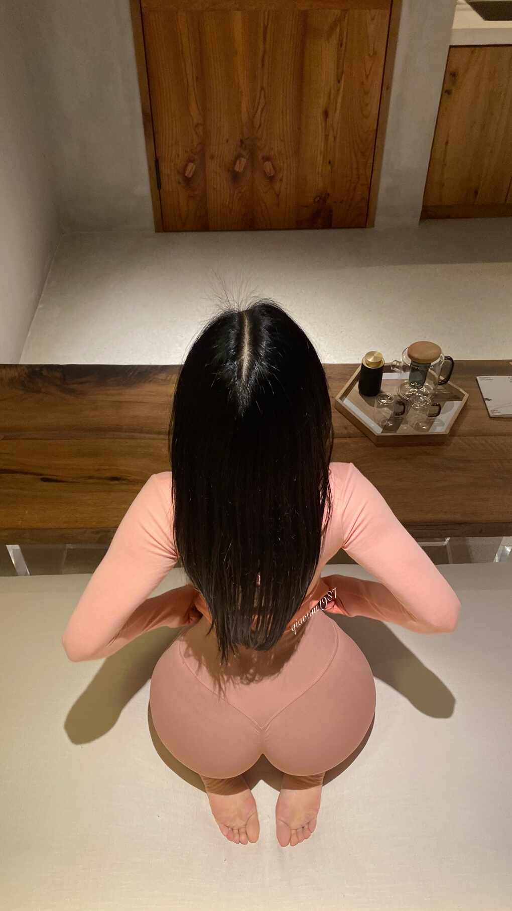 模特俏妞qiaoniuTT身穿粉色长袖瑜伽服和紧身瑜伽裤，从正后方拍摄的跪姿