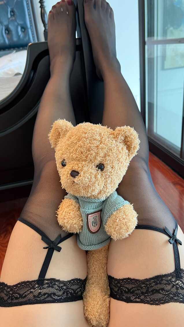 模特陈大小姐穿着黑色蕾丝吊带袜躺卧，将泰迪熊玩偶放在大腿之间，第一人称视角