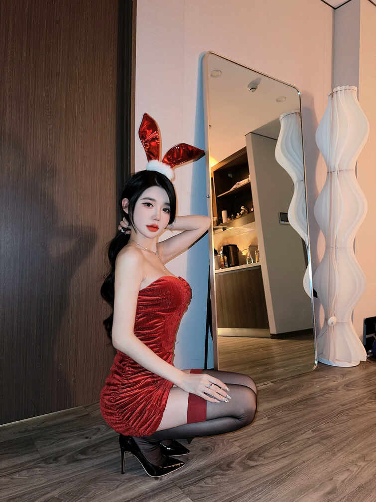 黎允熙baby头戴红色兔耳朵，身穿红色天鹅绒抹胸旗袍式连衣裙和黑色丝袜、黑色高跟鞋，在镜子前跪姿，优雅迷人。