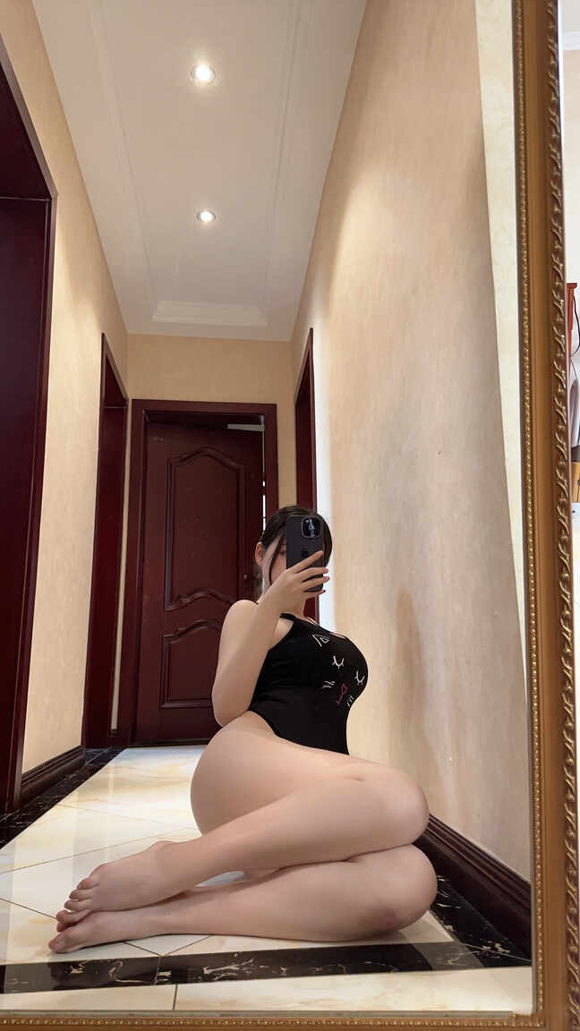 奶宝妹纸“猫咪连体衣镜前俏皮”嘉宾写真，身着黑色猫咪图案连体衣坐在地板上对镜自拍，展现慵懒随性的一面。