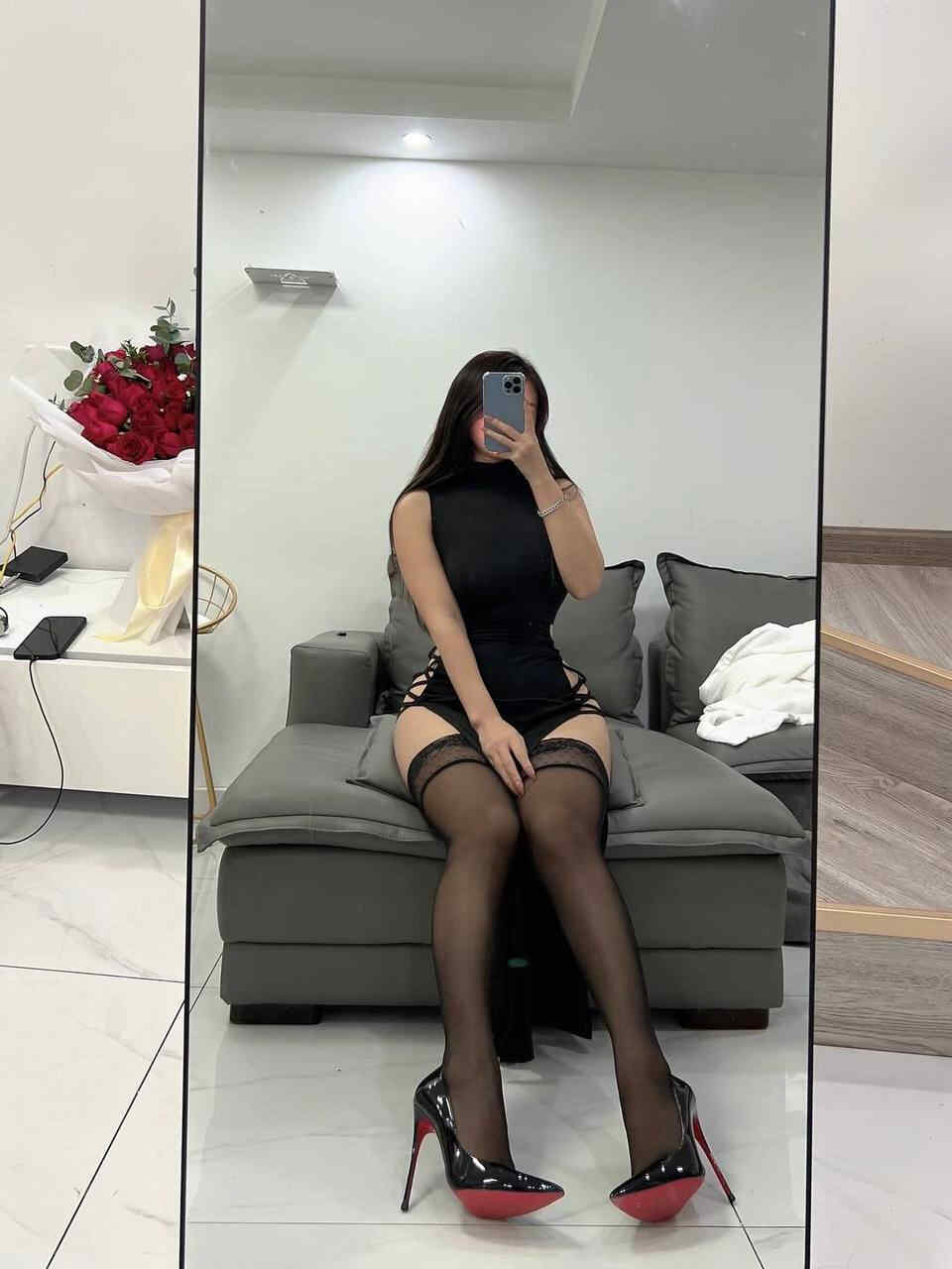 陈大小姐“黑裙蕾丝袜镜前光影秀”VIP写真，身着黑色开衩裙与蕾丝丝袜在沙发上进行多角度镜前自拍，背景有红色玫瑰花束点缀。
