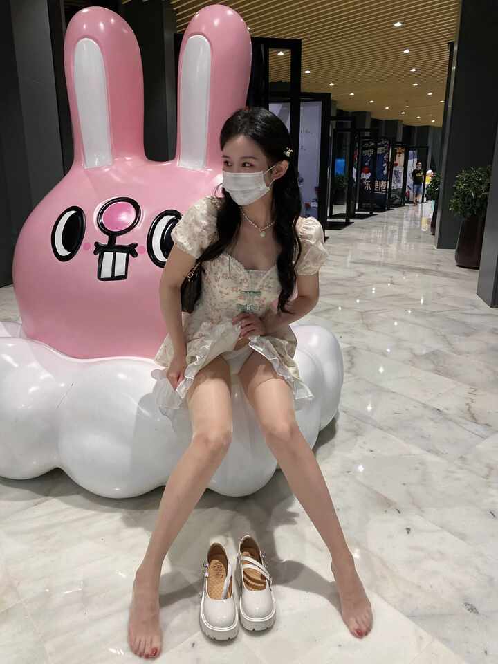 July芝岚“碎花裙玛丽珍鞋玩偶奇遇”主题，身着碎花连衣裙与肤色丝袜，坐在彩色长椅上整理白色玛丽珍鞋的搭扣，展现侧面造型与精致细节。