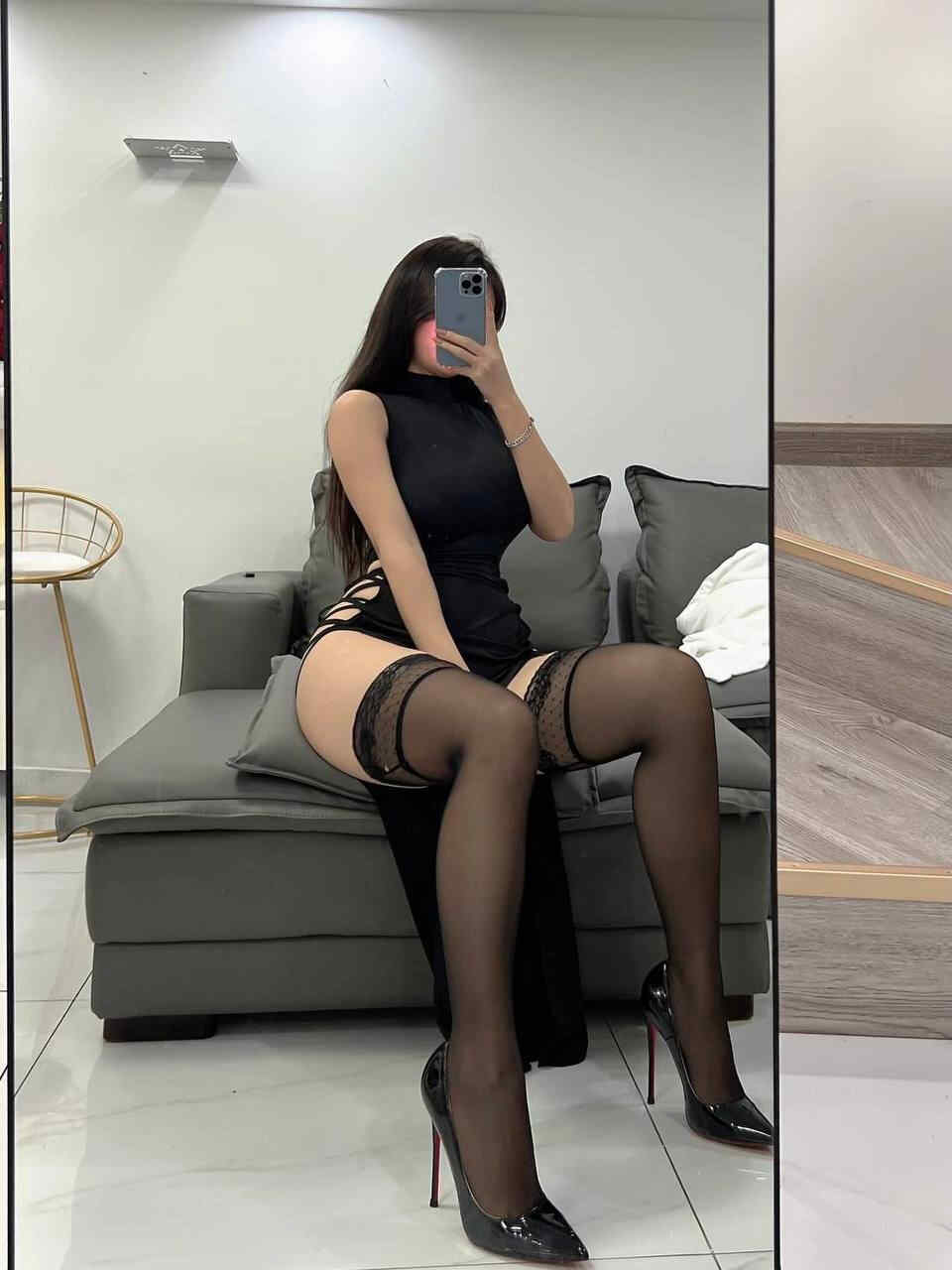 陈大小姐身着黑色高开衩无袖连衣裙搭配蕾丝花边过膝丝袜与红底高跟鞋，在沙发上进行镜前时尚自拍，展现“黑裙蕾丝袜镜前光影秀”的优雅与魅惑。