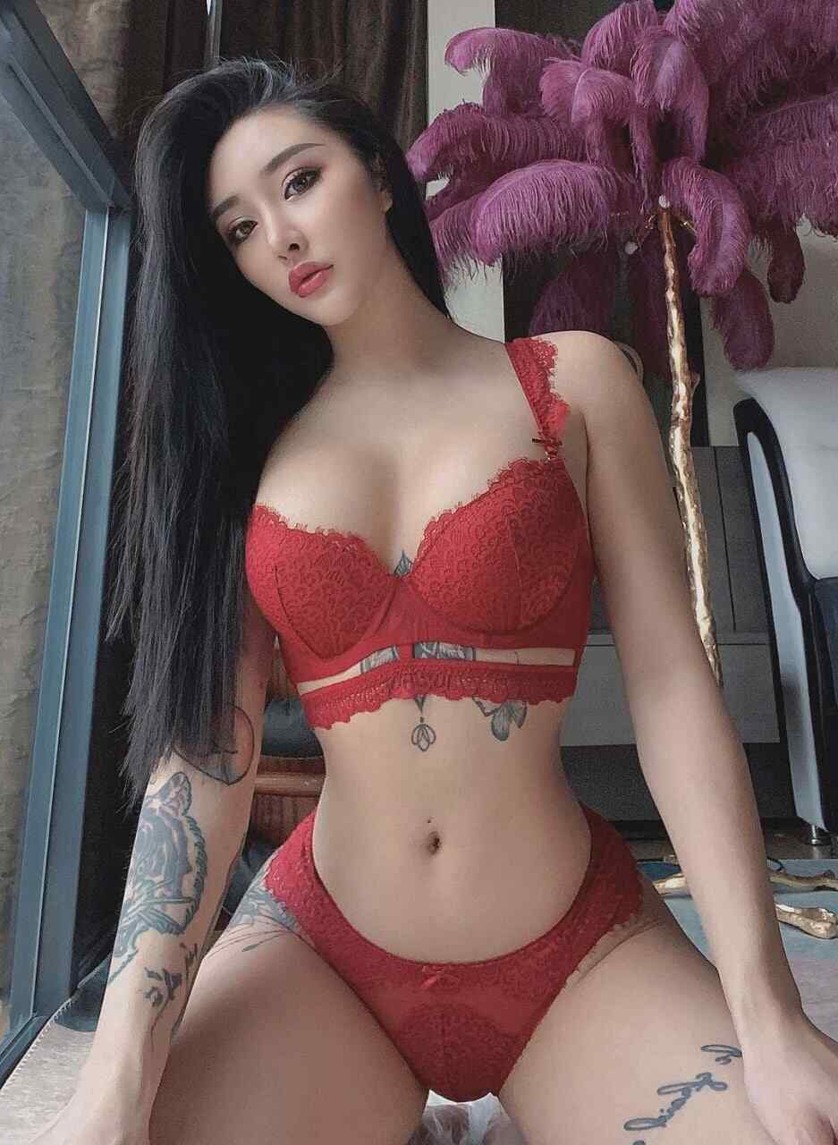 宋昱欣“红色蕾丝纹身艺术”主题，身着热情的红色蕾丝套装，在华丽背景（如羽毛灯饰）前展现迷人风情与个性纹身