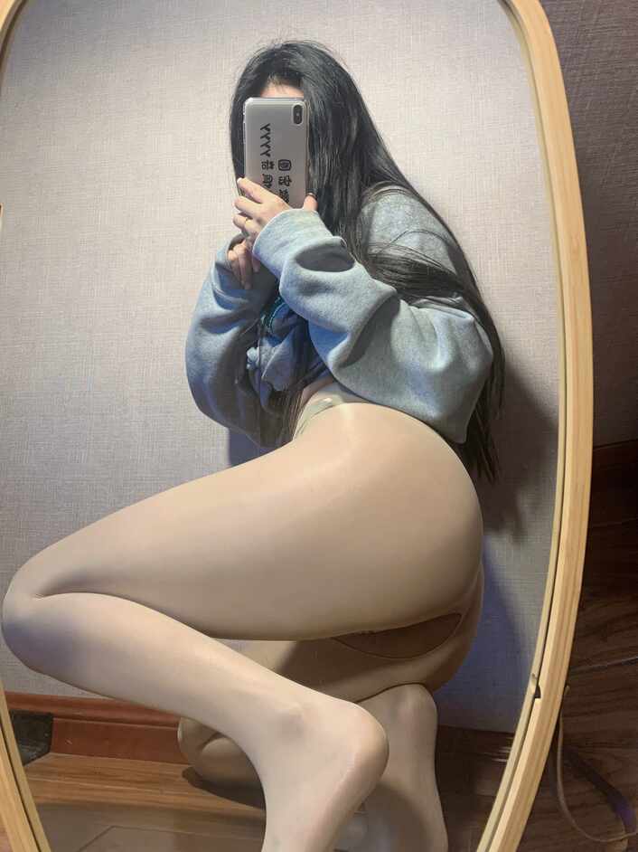 陈佩奇yyyy“光泽丝袜豹纹居家自拍”主题，身着灰色卫衣与光泽感肉色丝袜，在镜子前呈侧身跪姿自拍，突出丝袜的光泽与腿部线条。